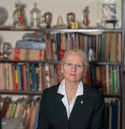 Photograph of the doctor in a suit before a bookcase. 